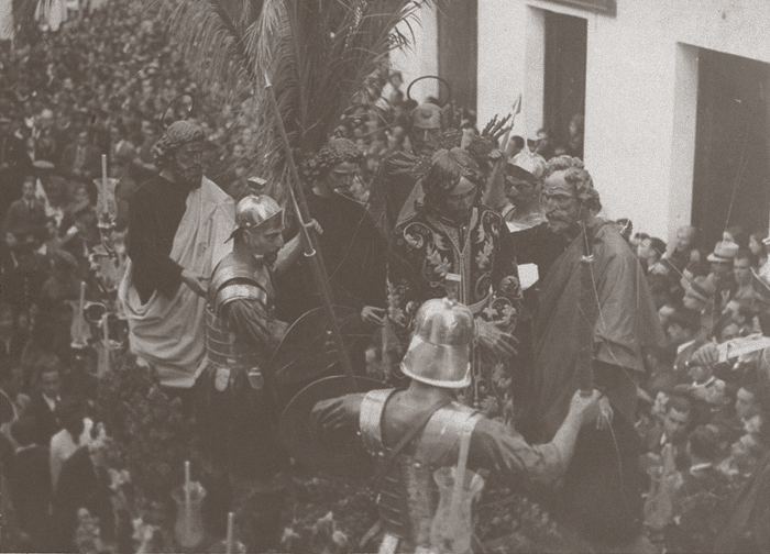 Por la Calle Orfila y a poco de haber salido desde su Capilla de San Andrés, contemplamos al antiguo misterio panadero del Prendimiento en la tarde de un Miércoles Santo de en torno a 1930, presidido por la Imagen del Señor que hoy se venera en la Parroquia del Juncal.