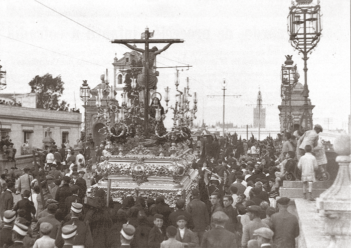 Bajo las catenarias de los tranvías y ya con su nuevo canasto, vemos al antiguo Cristo de la Salud cruzando el Puente de San Bernardo en la tarde del Miércoles Santo de 1928, en el que por última vez figuró la Magdalena de Ordoñez a sus piés. Fotografía: Hdad de San Bernardo.