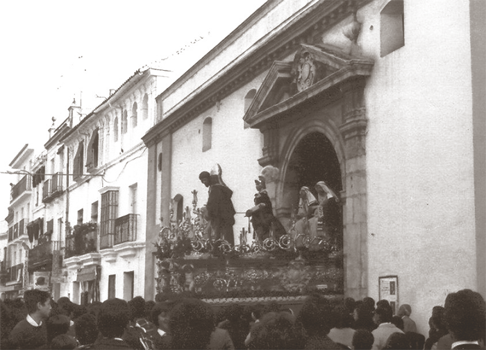 Mañana del Jueves Santo de 1976, en la Calle Castilla vemos saliendo el paso de misterio de la San Gonzalo desde el interior del Templo de La O, en el que a causa de la lluvia tuvo de resguardarse.