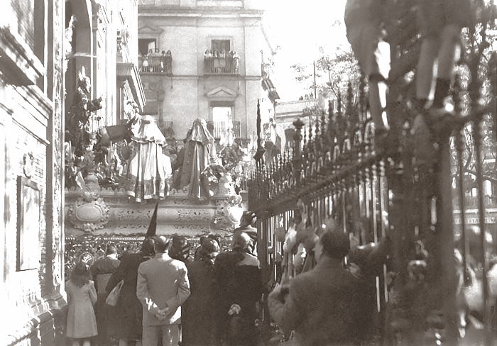 El Señor de la Sagrada Entrada en Jerusalén saliendo desde El Salvador. Llovió el Domingo de Ramos de 1945 y la Hermandad del Amor procesionó dos días más tarde -algo impensable hoy en día. Aquí vemos, que en aquella tarde de Martes Santo procesionó con el canasto de Francisco Posadas Benítez, a medio terminar, sin dorar.